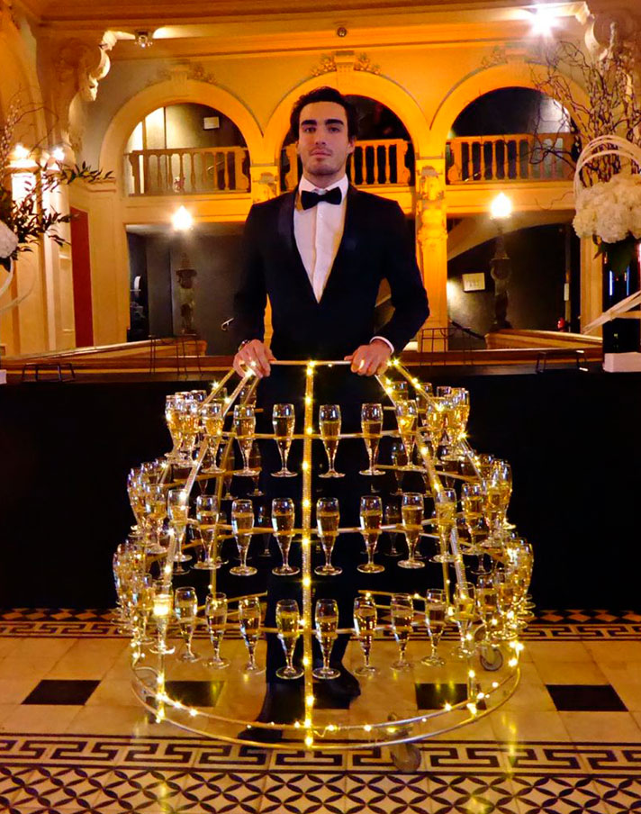 Homme élégant en smoking distribuant des flûtes de champagne lors d'un événement haut de gamme