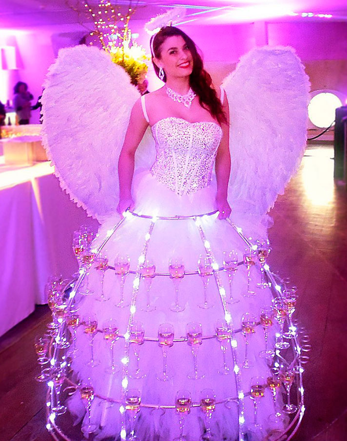 Lady Champagne en costume d'ange avec robe blanche et ailes lumineuses